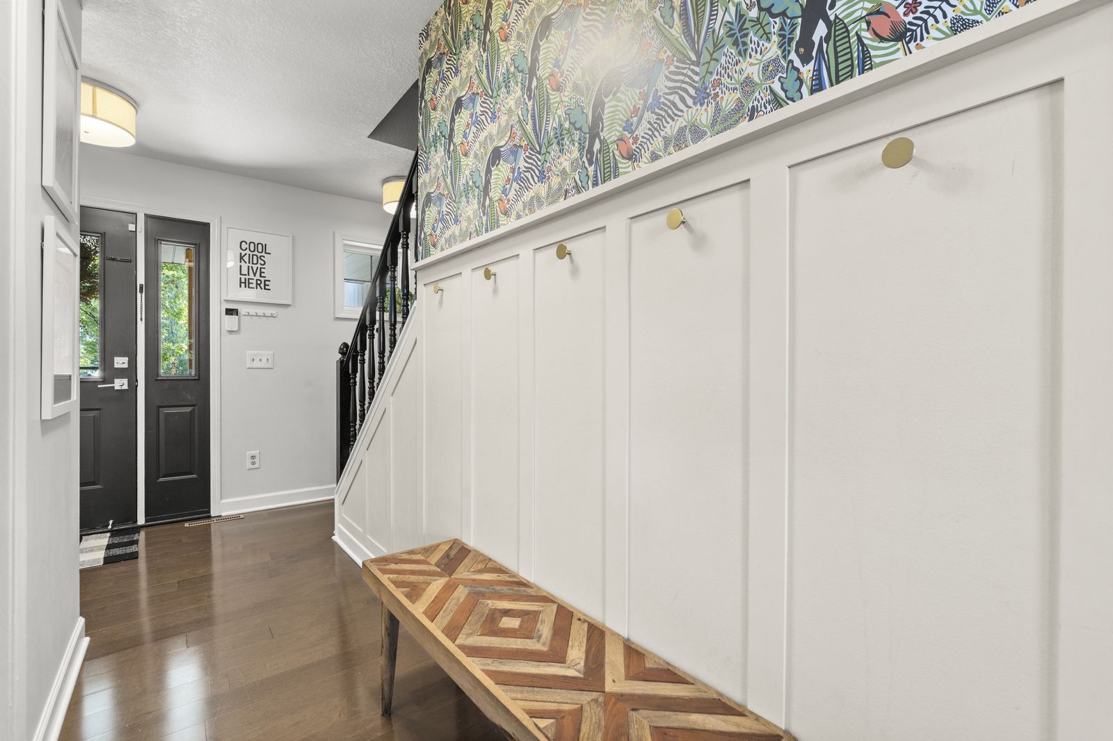 Entry foyer with staircase and patterned wallpaper accent