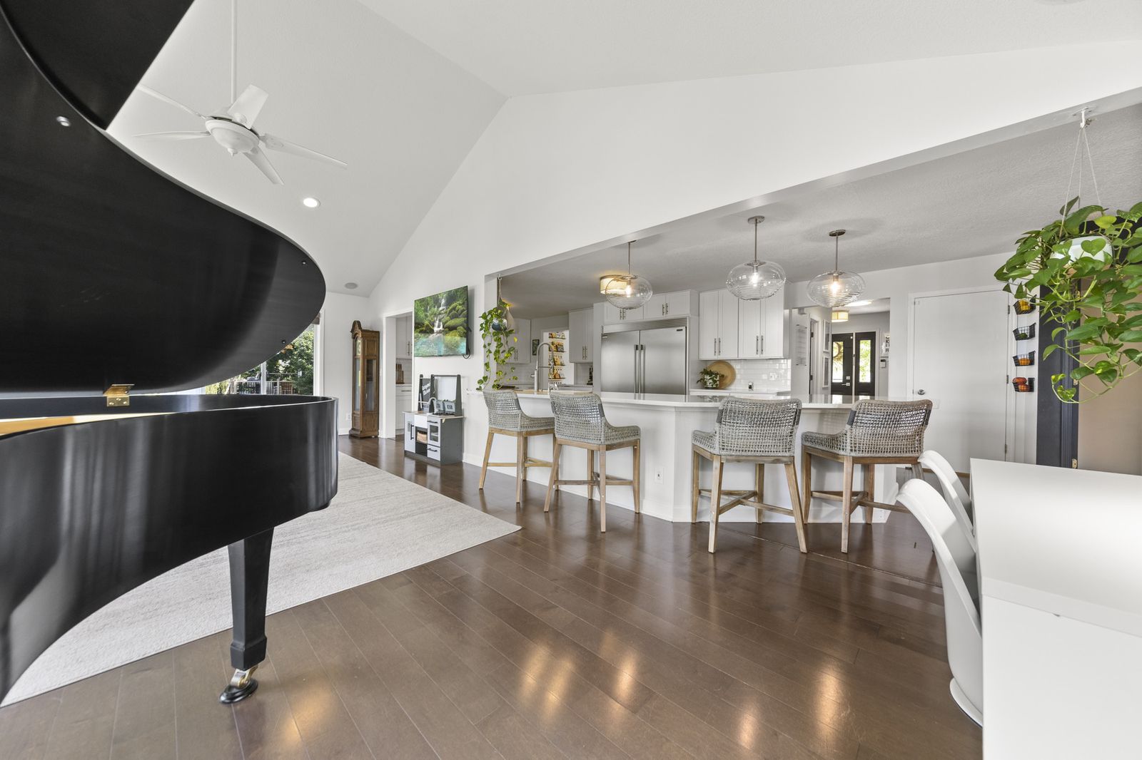 Living room with vaulted ceiling and grand piano, open to kitchen