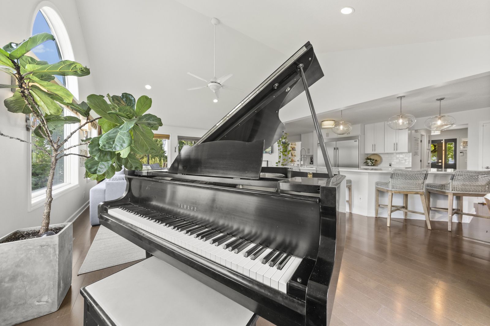 Living area with grand piano and view into kitchen