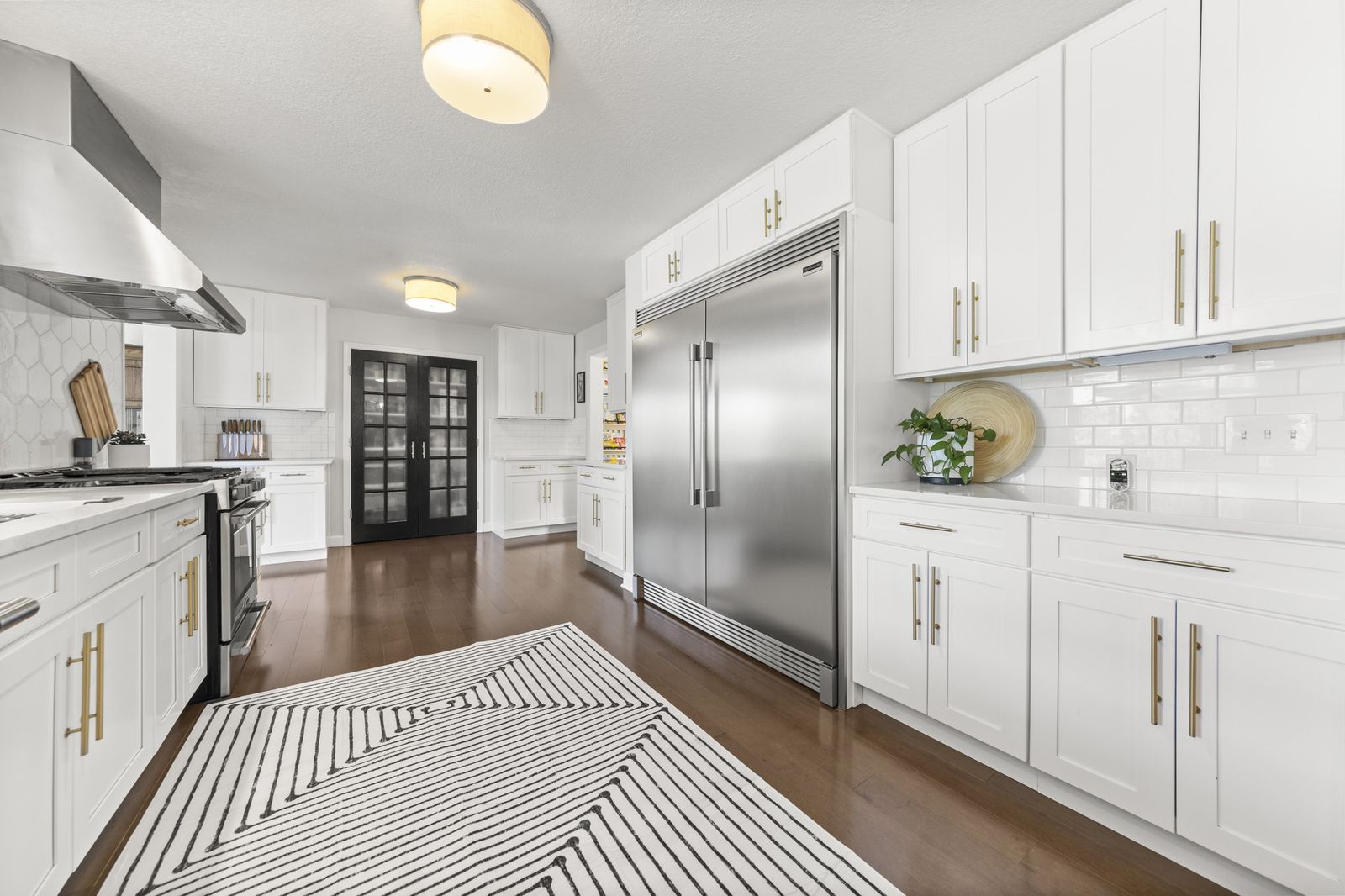 Kitchen view toward dark French doors and stainless fridge