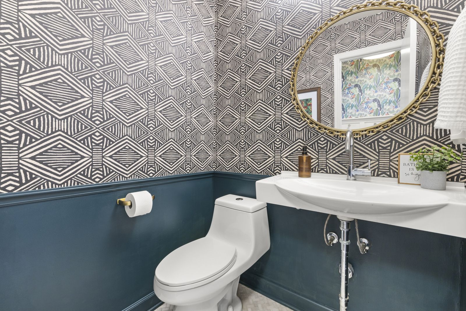 Powder room with patterned wallpaper and dark vanity