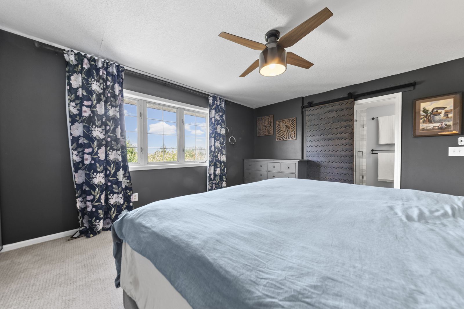 Bedroom with floral curtains and dark accent wall
