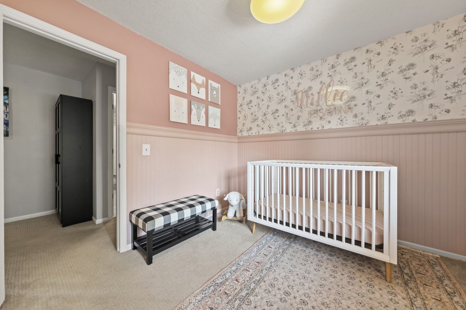 Bedroom with pink accent wall and crib, alternate view