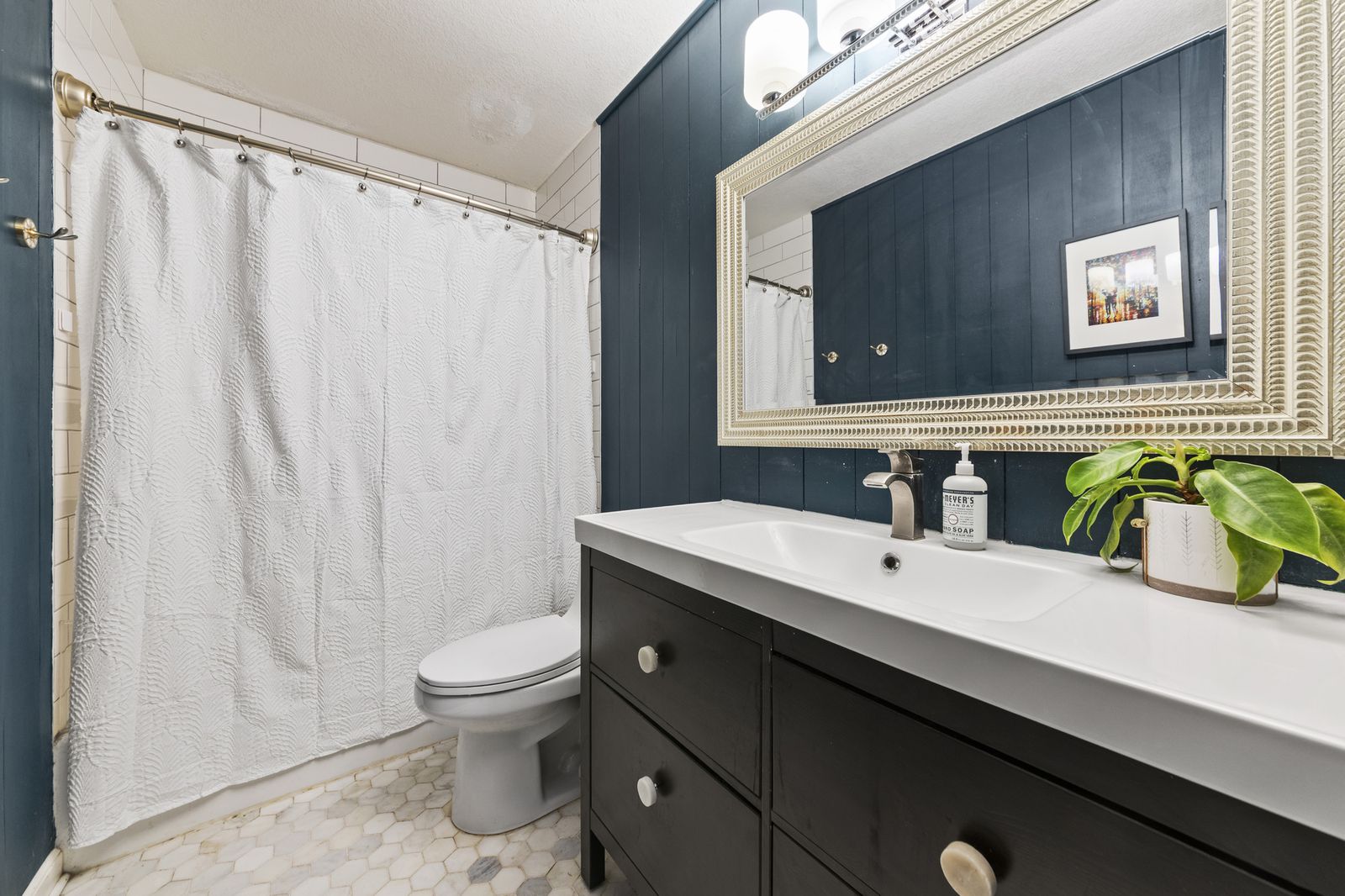 Bathroom with dark blue vanity and shower curtain
