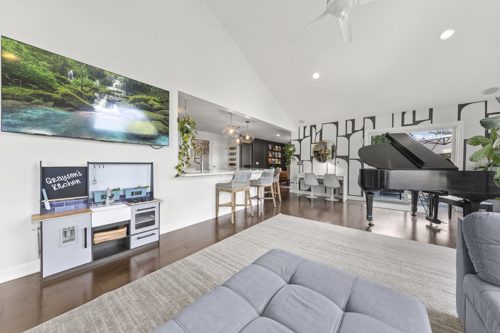 Lower level family room with wall-mounted TV and piano