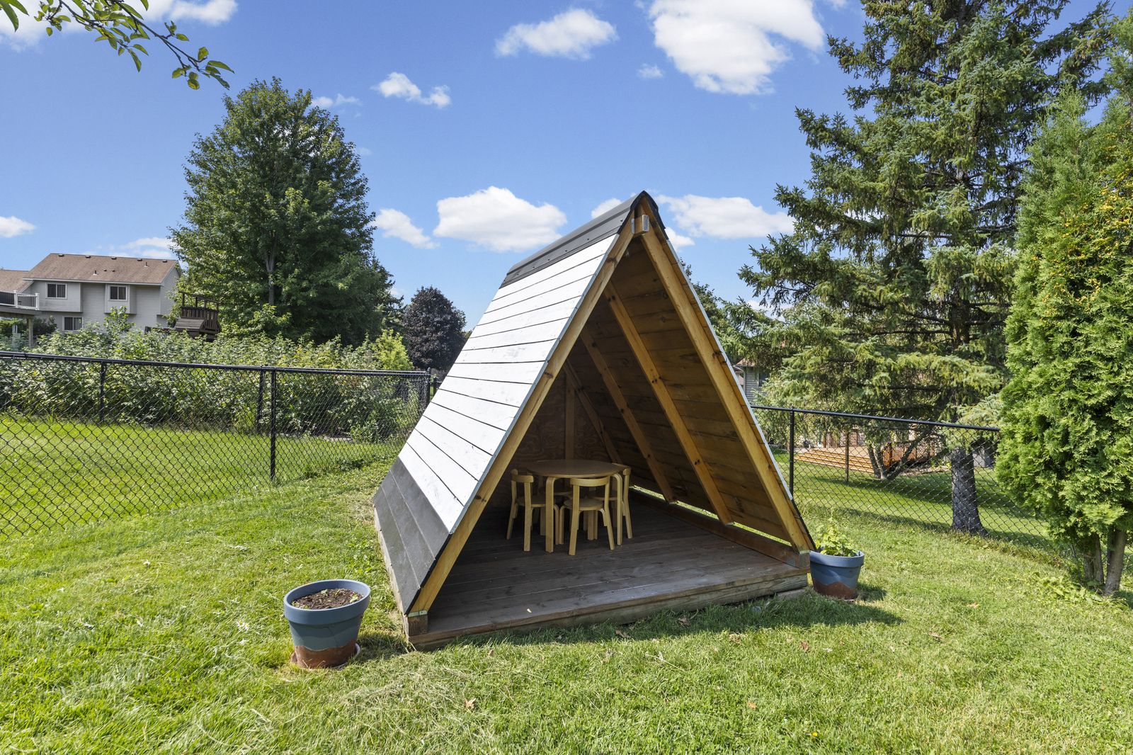 Wooden A-frame playhouse in backyard