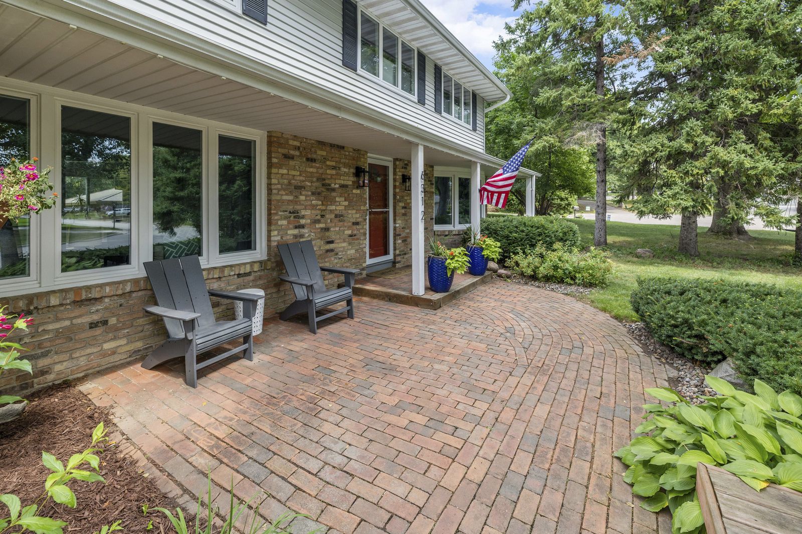 Front porch with brick paver walkway and seating
