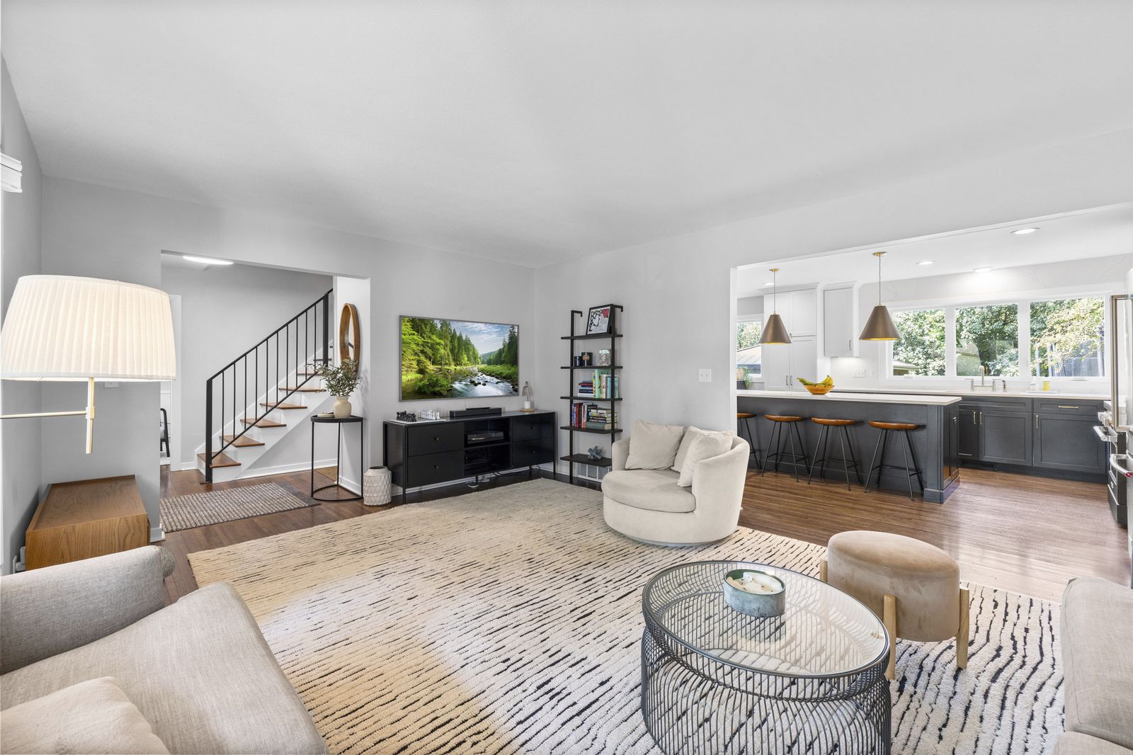 Open living area with kitchen and staircase visible, virtually staged