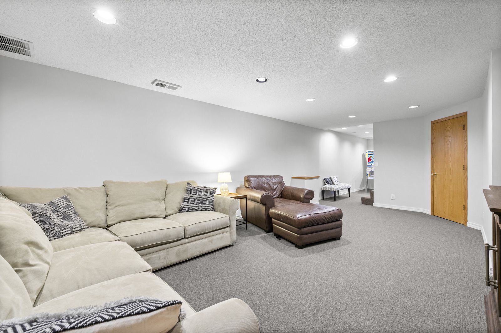 Lower level family room with seating and neutral carpet