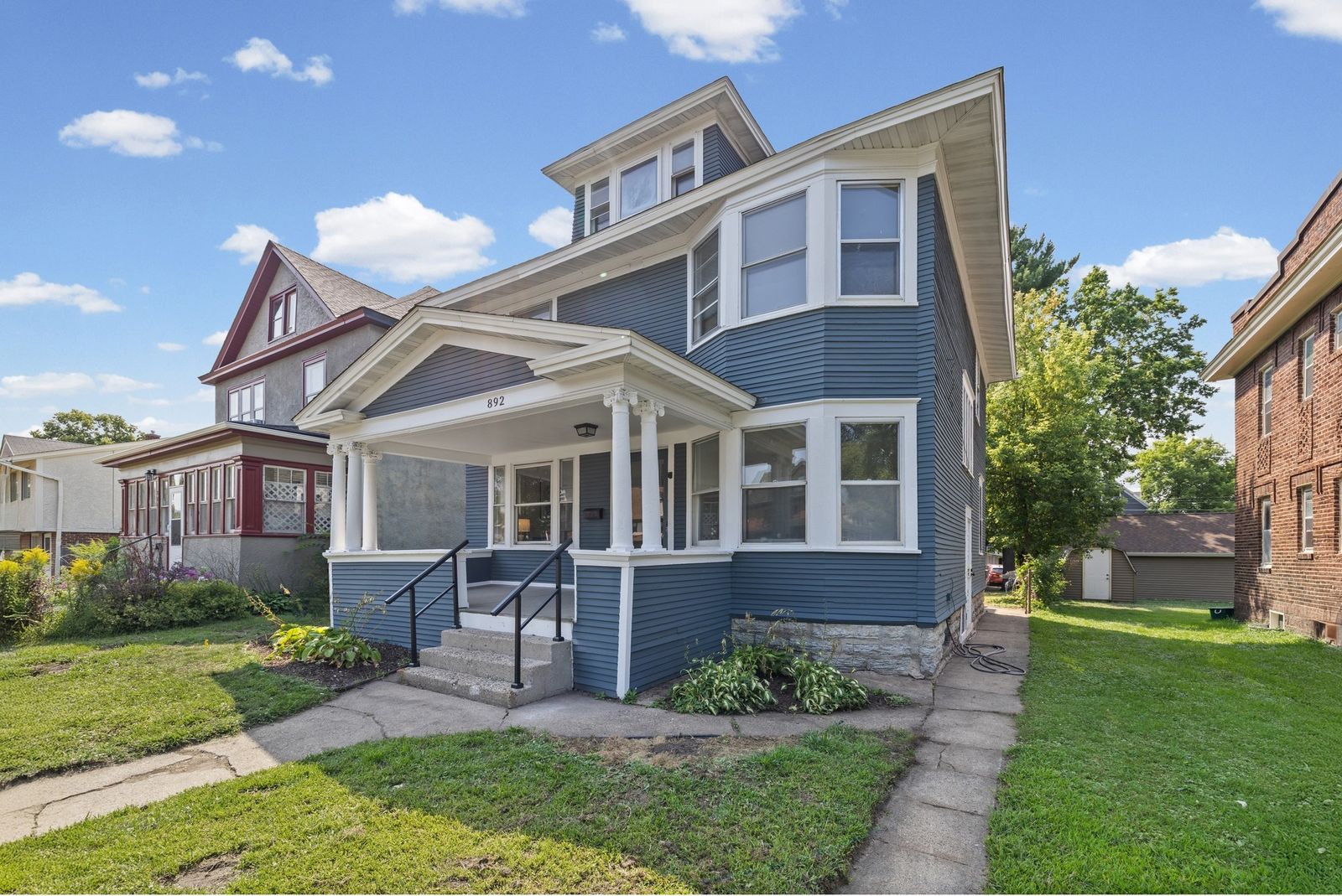 Front exterior of blue two-story house with covered porch, daytime