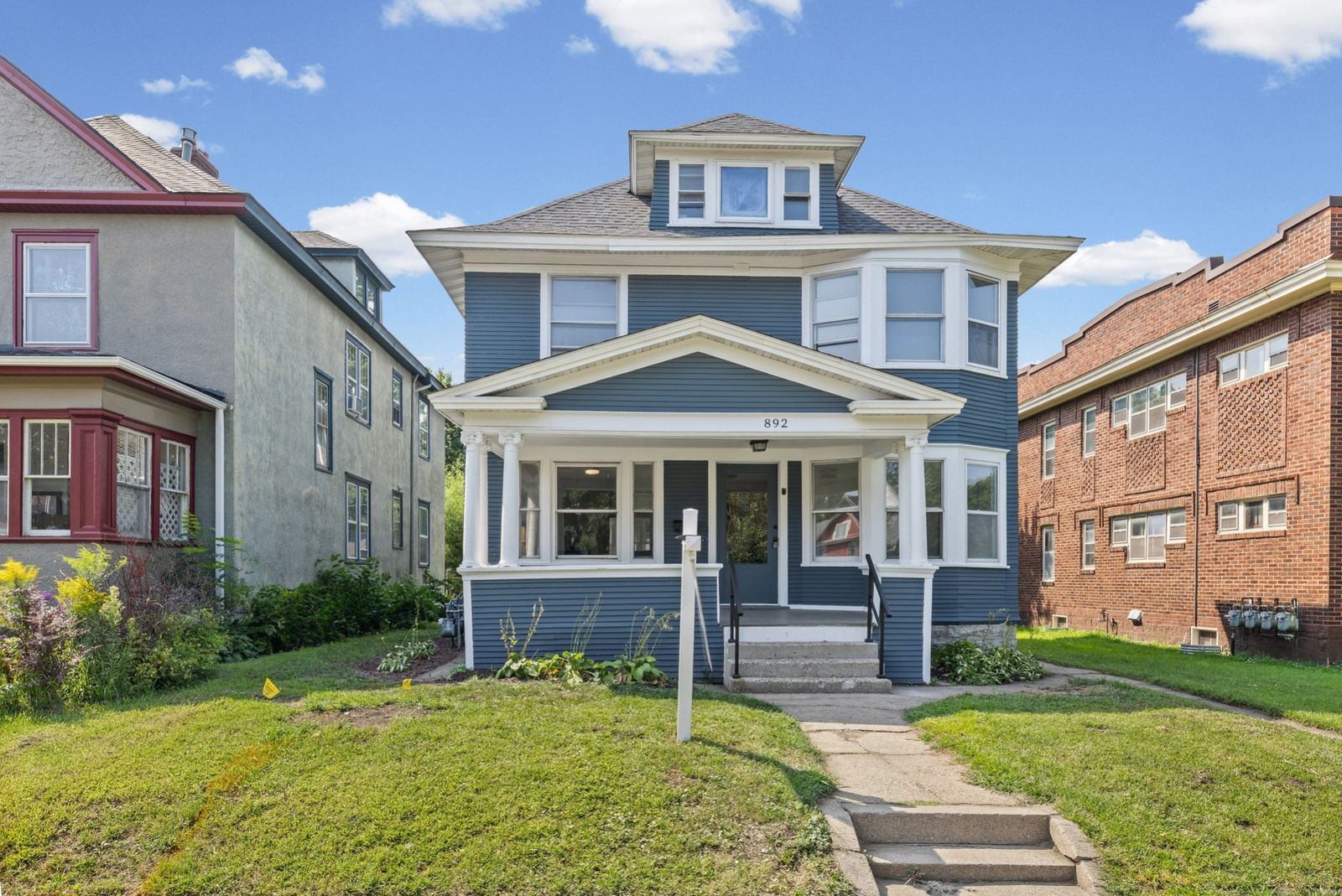 Front exterior of blue house with columned porch, daytime wide view