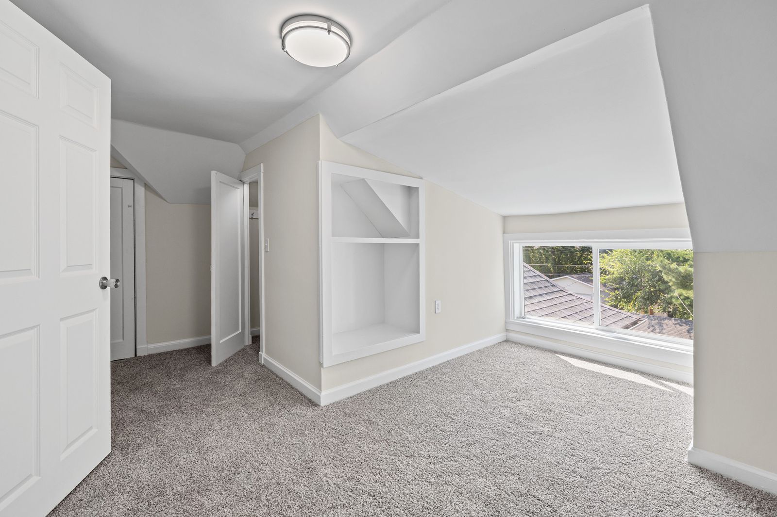 Upstairs bonus room with sloped ceiling and built-in shelving