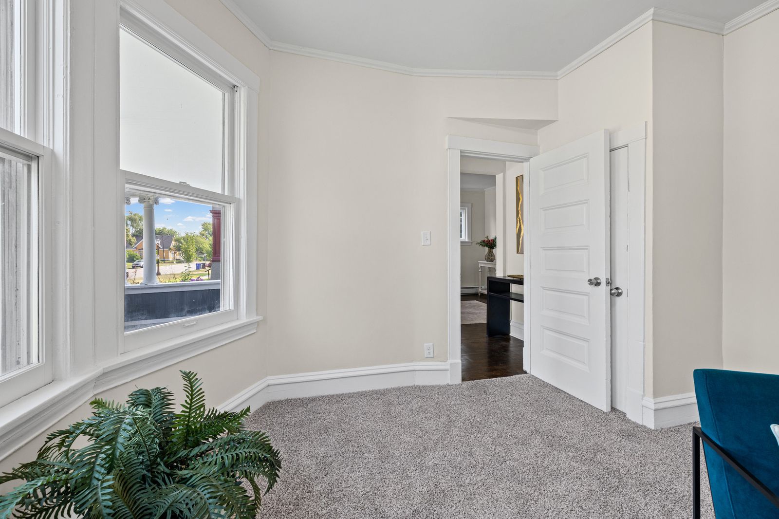 Upstairs room with bay window, virtually staged with plant and rug