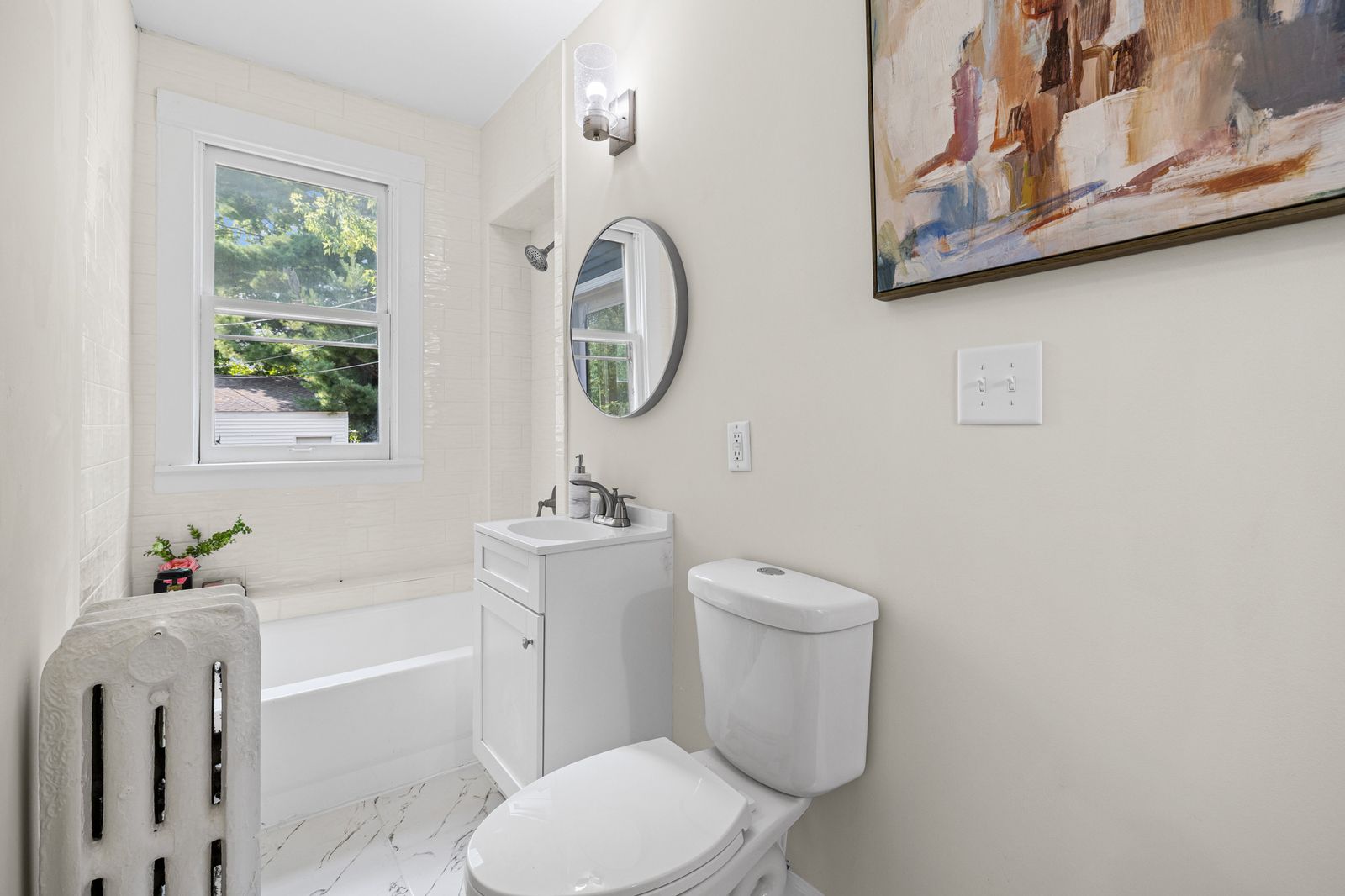 Upstairs bathroom with tub and round mirror