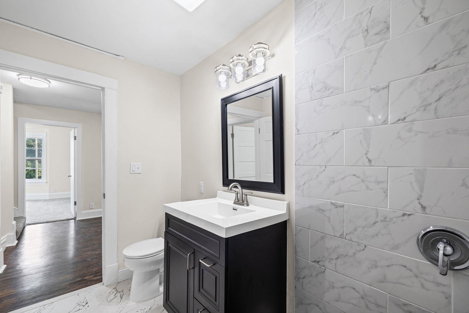 Bathroom with marble tile and dark vanity, alternate view